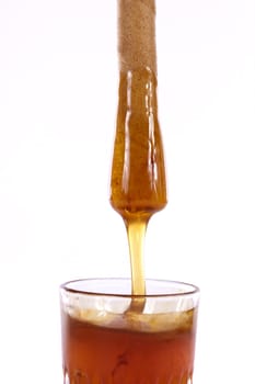 Close up view of a glass of honey with cookie roll isolated on a white background.