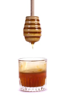 Close up view of a glass of honey with dipper isolated on a white background.