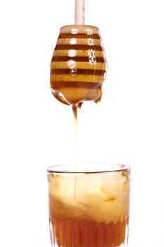 Close up view of a glass of honey with dipper isolated on a white background.