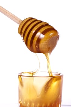 Close up view of honey dipper with honey dripping isolated on a white background.