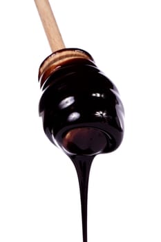 Close up view of a honey dipper with dark chocolate isolated on a white background.