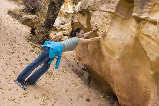 Helplessness - young girl trying to push a huge rock.