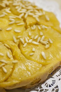 Close view of a homemade pineapple cake decorated with pine nuts.