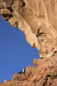 Tourist resting under North Window in Arches National Park.