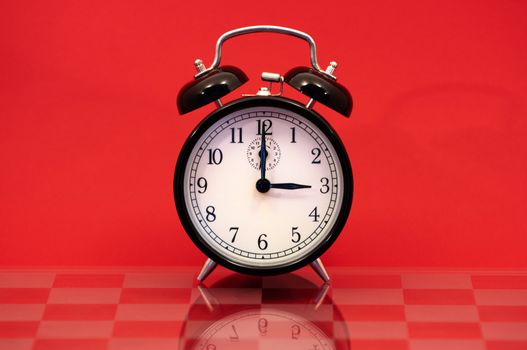 Vintage Alarm Clock Showing 3 O'Clock Isolated on a Red Background.