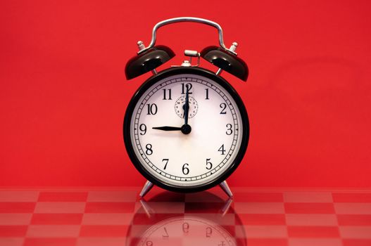 Vintage Alarm Clock Showing 9 O'Clock Isolated on a Red Background.
