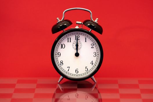 Vintage Alarm Clock Showing 12 O'Clock Isolated on a Red Background.