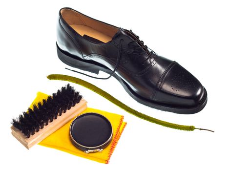 Shoe shine concept with shiny black men's shoe, black polish, brush and yellow duster