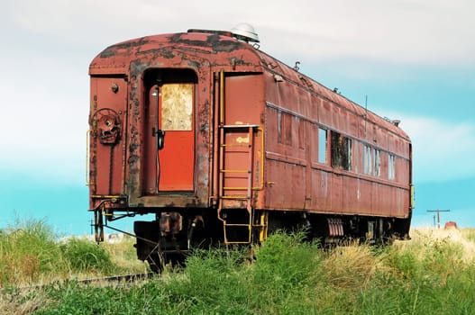 Rusted and worn out, an old passenger railcar sits on a rail siding.
