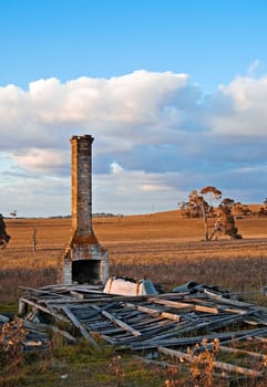 all that is left of this old farmhouse is a chimney, a pile of wood and an upturned bath