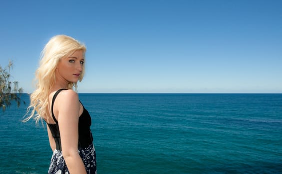 beautiful young woman looks over the ocean 