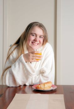 young woman having juice and crossiant for breakfast