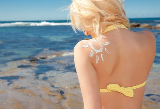 a beautiful young blonde woman at the beach with sunscreen sun