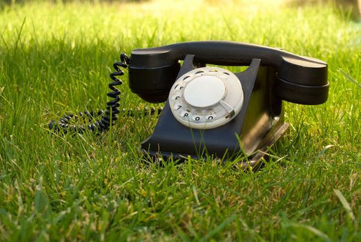 Retro styled rotary telephone in the grass