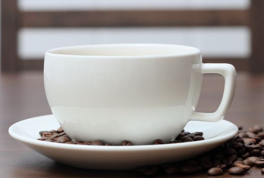 White cup with coffee beans on the table