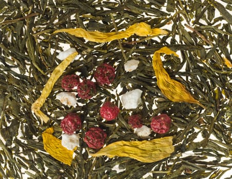 Background image consisting of tea leaves and dry fruits with focus on berries
