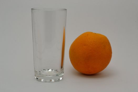 The empty glass and the orange over white background