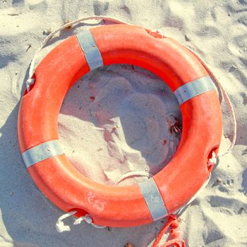 Orange life buoy over sand on the shore