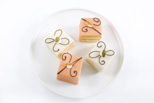 Close up of four petits fours on white plate.