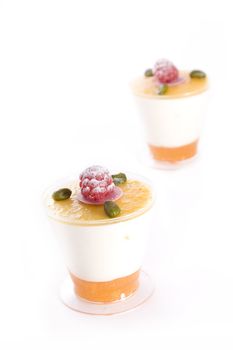 Two cups of mango vanilla mousse with raspberry and pistachio topping.