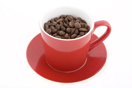 Red coffee cup with saucer full of coffee beans.  