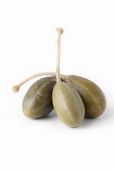 Three large capers isolated on white background with vertical orientation.