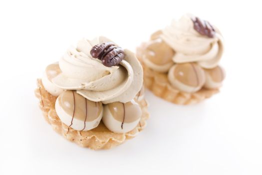 Small pie pastries with cream chocolate and caramel toppings and Pecans.  Isolated on white.