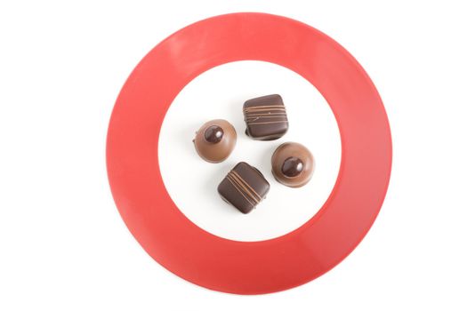 Four Gourmet Chocolates on Red Rimmed Plate.  The shot is studio isolated on a white background