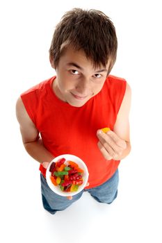 Boy eating a jelly baby from a bowl of mixed coloured lollies candy.  