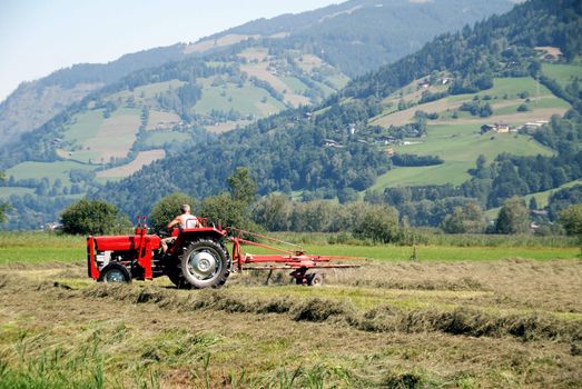 Tractor plowing in front of mountains in austrian farm