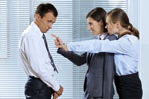 Businesswomen shouting at businessman in office
