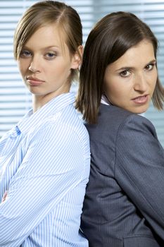 Portrait of businesswomen standing back to back in office