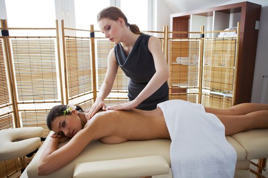 Portrait of young woman receiving massage from masseuse