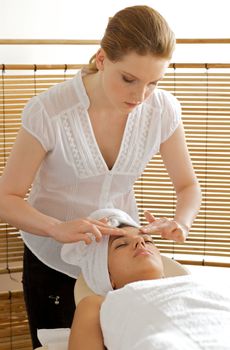 Young woman receiving head massage from masseuse