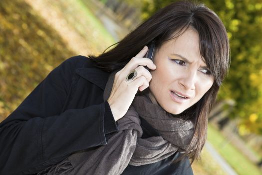 Surprised girl on the phone in the colorful park.