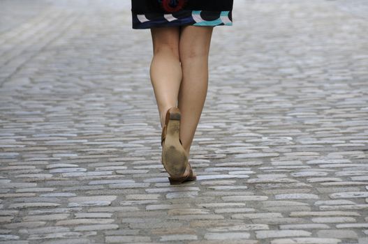 Shot of woman legs walking on cobbled pavement.