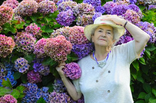 Old senior woman with hat showing her flowers.