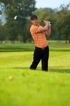 Young man swinging golf club
