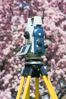 Spring surveying - theodolite against blosoming tree.