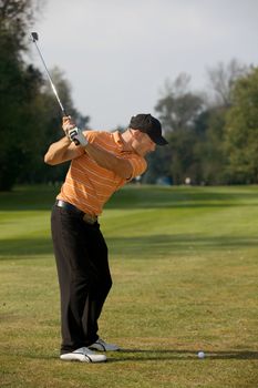 Young man swinging golf club