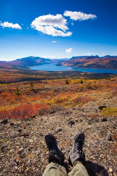 Legs and boots of Hiker resting in tundra colored yellow and red by fall.