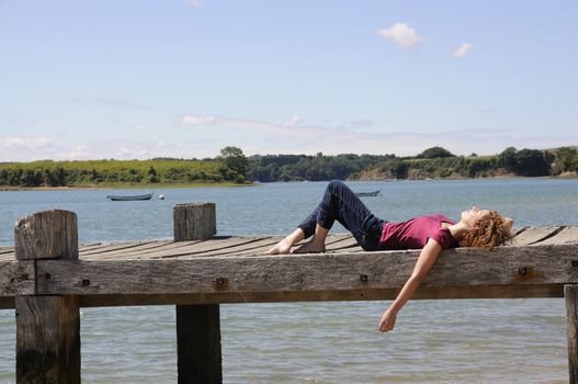 Pretty girl lying and relaxing on landing stage in Brittany, France on a sunny day.