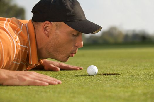 Close-up of man blowing on golf ball