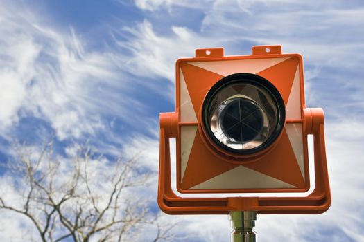 Prism againts cloudy sky - spring land surveying.