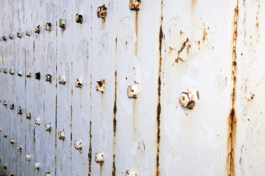 Rusty metal wall with bolts background.