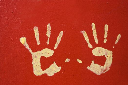 Yellow hands on red, metal wall.