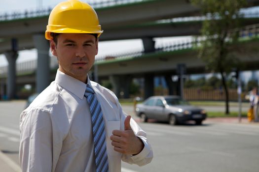 Portrait of architect in hardhat showing thumbs up sign at construction site