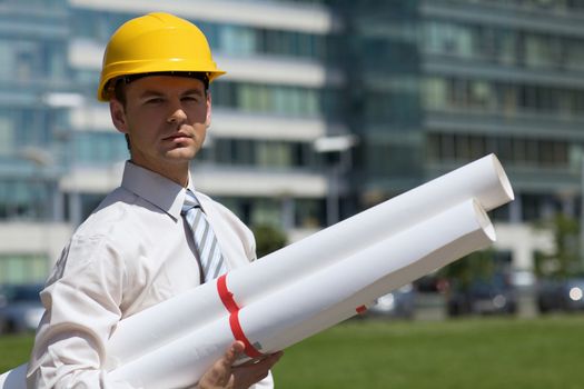 Portrait of architect in hardhat holding blueprint at construction site