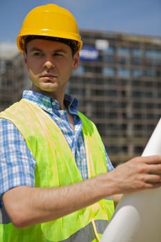 Engineer holding blueprint at construction site