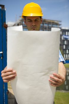 Engineer holding blueprint at construction site